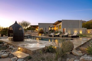 A modern house with a swimming pool, outdoor seating, and a unique spherical structure.
