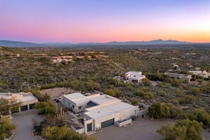 Una zona residencial con casas modernas, cielo despejado y montañas al fondo.