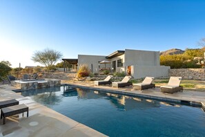A modern house with a swimming pool, outdoor seating, and a stone wall. - Catalina Clubhouse | Luxury Retreat in Tucson | Fieldtrip (Tucson)