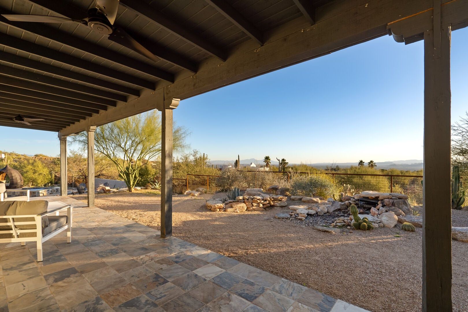 An outdoor patio with a pergola, a stone table, and a view of a desert landscape.