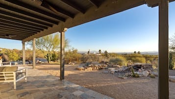 An outdoor patio with a pergola, a stone table, and a view of a desert landscape.