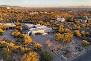 A desert landscape with modern buildings, including a large structure with a flat roof and a smaller building with a garage. - Catalina Clubhouse | Luxury Retreat in Tucson | Fieldtrip (Tucson)