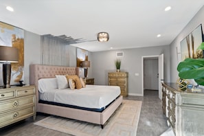 A bedroom with a bed, nightstands, a dresser, and a large painting on the wall.