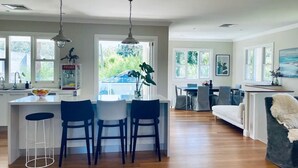 A spacious living area with a kitchen island, bar stools, and a dining table.