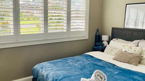 A bedroom with a bed, a ceiling fan, and a window with blinds.