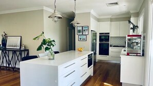 A modern kitchen with white cabinetry, a central island with drawers, and a dining area with a table and chairs.