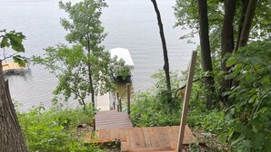 A wooden staircase leading to a dock over water, surrounded by trees and greenery.