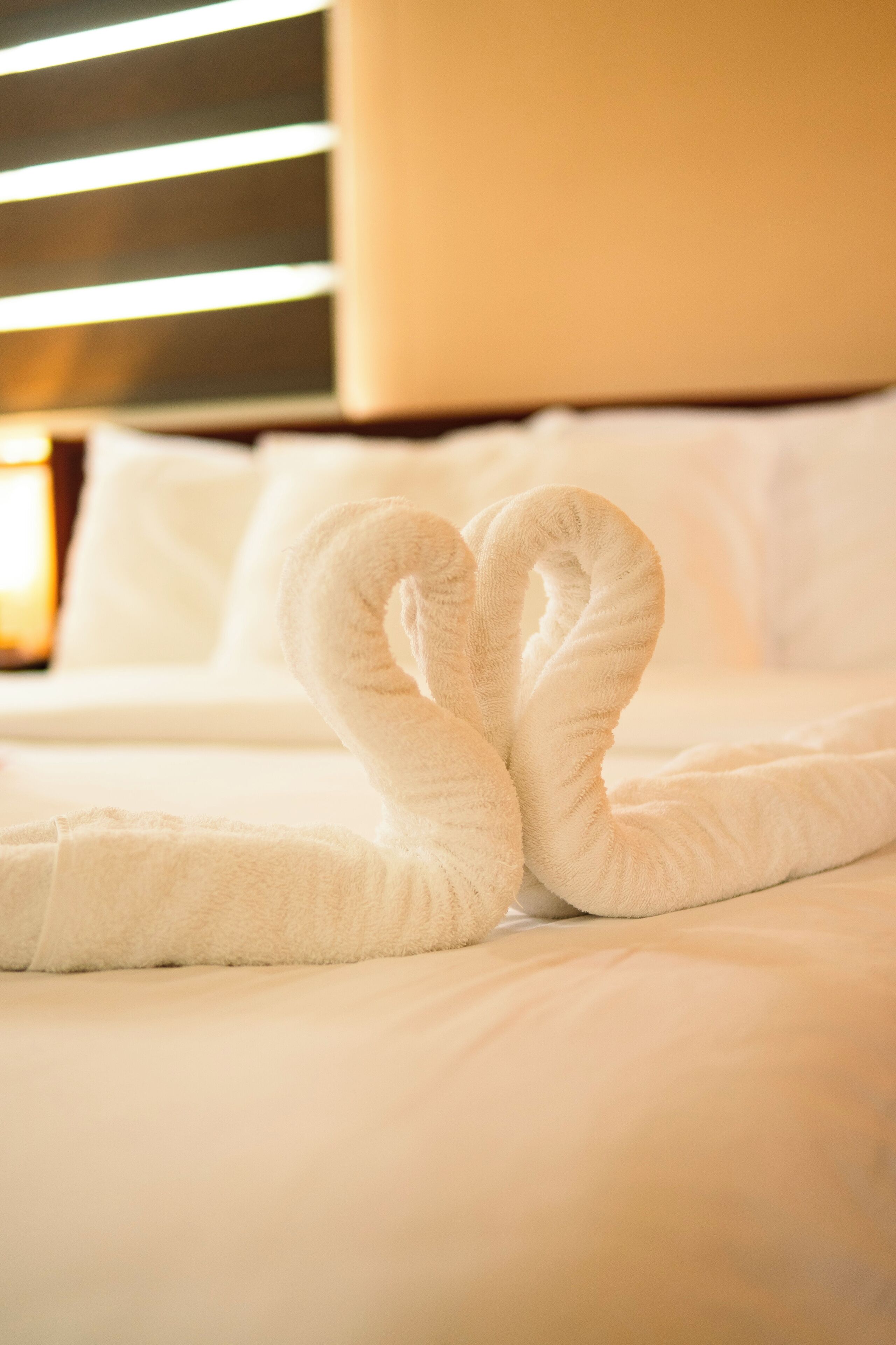 Una cama bien hecha con una toalla dispuesta en forma de corazón.