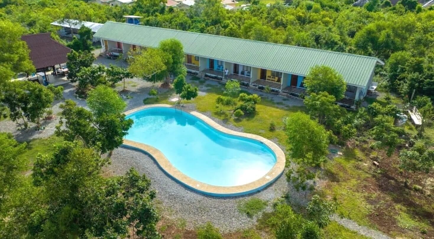 An aerial view of a hotel with a swimming pool surrounded by trees.