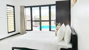 A bedroom with a bed, a window with blinds, a view of a swimming pool, and a wall-mounted artwork. - Paradise Villas (Nadi)