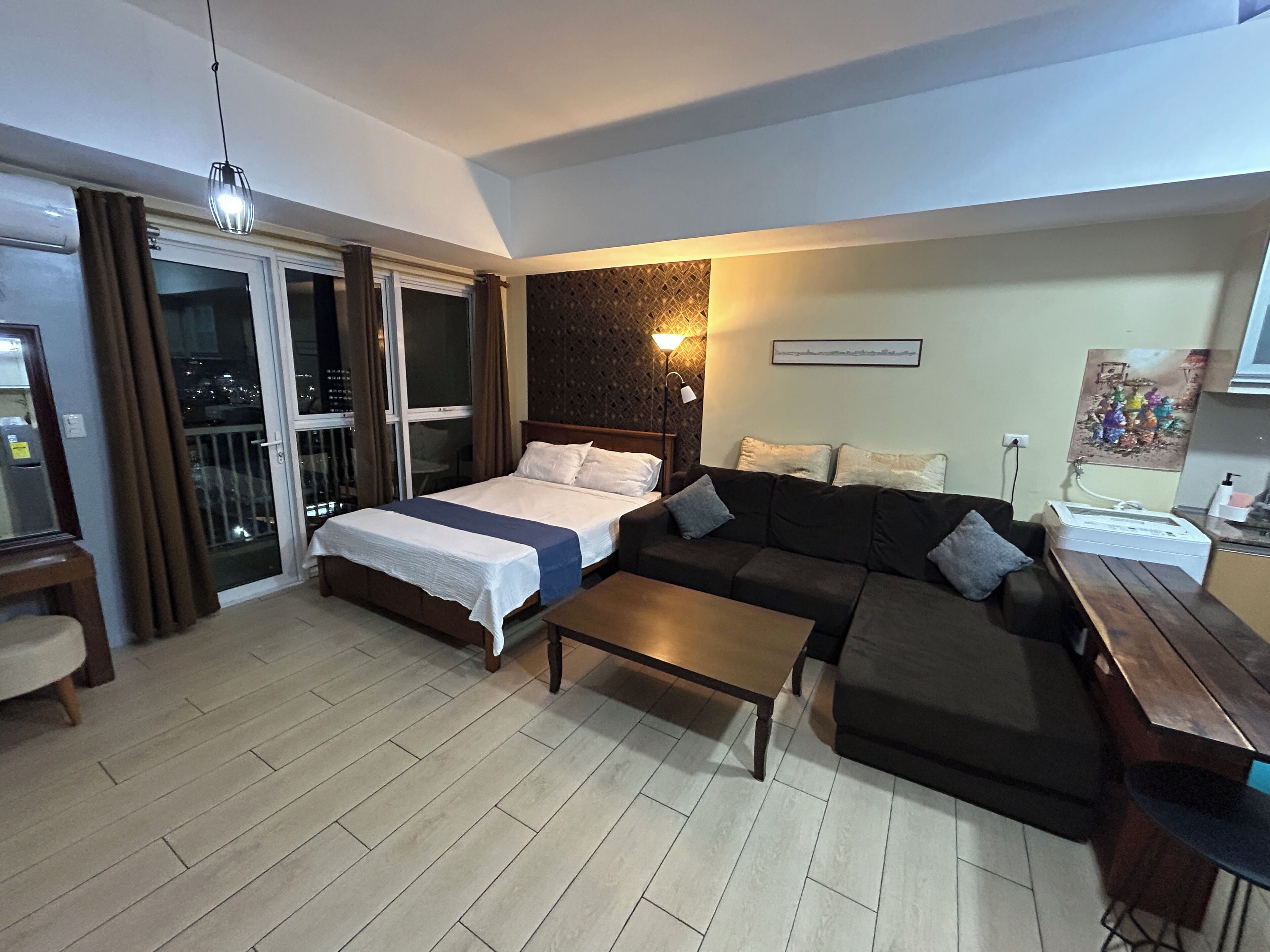 A modern hotel room with a bed, a sofa, a coffee table, and a desk.
