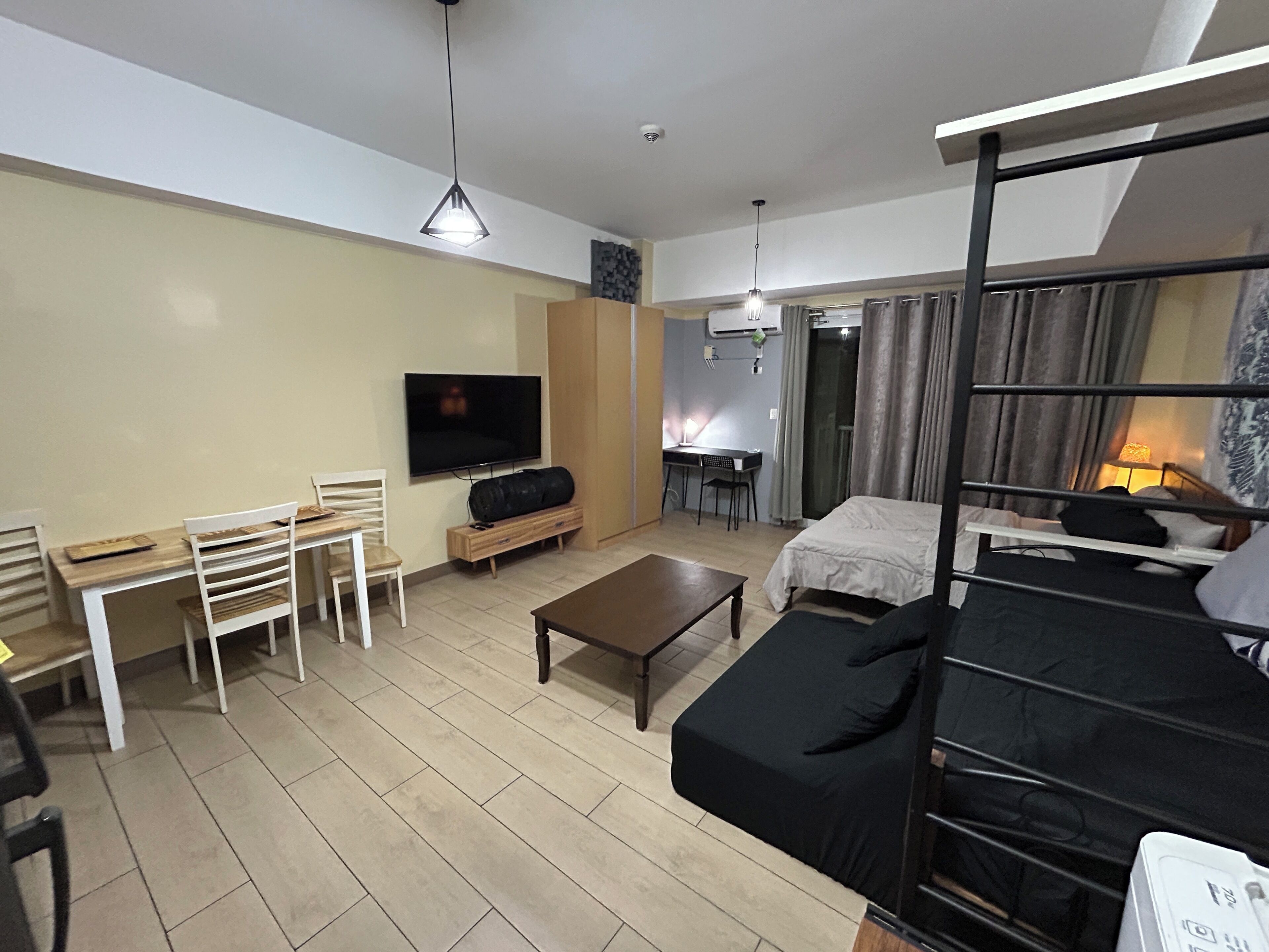 A compact living space with a TV, a small dining table, a sofa, and a bunk bed.
