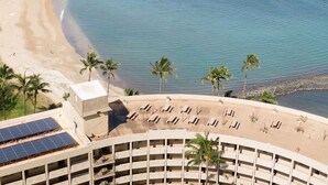 Ein Hotel mit Blick auf den Strand, mehreren Etagen und einem Poolbereich mit Liegestühlen.