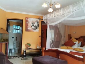 A bedroom with a bed, a nightstand, a painting, and a ceiling fan. - Roddy Hotel Kisumu (Buyangu)