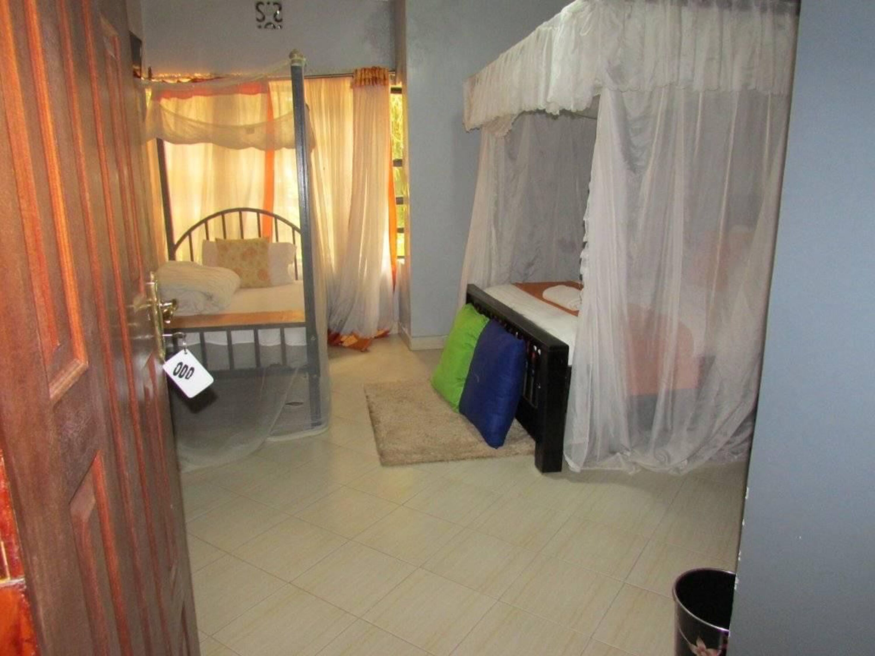 A bedroom with a bed, a nightstand, a window with curtains, and a door.