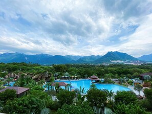 A resort with a large swimming pool, lush greenery, and mountains in the background. - Regal Palace Resort&Spa (Guangzhou)