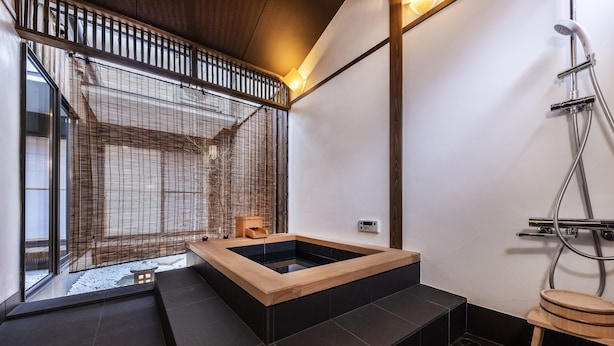 Une salle de bain moderne avec une baignoire en bois, une douche et une vue sur un espace extérieur enneigé.