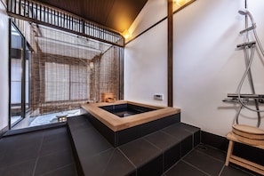 Ein modernes Badezimmer mit einer Holzwanne, einer Dusche und Blick auf eine verschneite Landschaft.