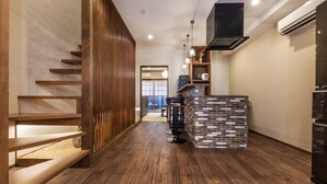 Une cuisine moderne avec un plancher en bois, un mur décoratif en briques apparentes et un îlot central doté de tabourets de bar.