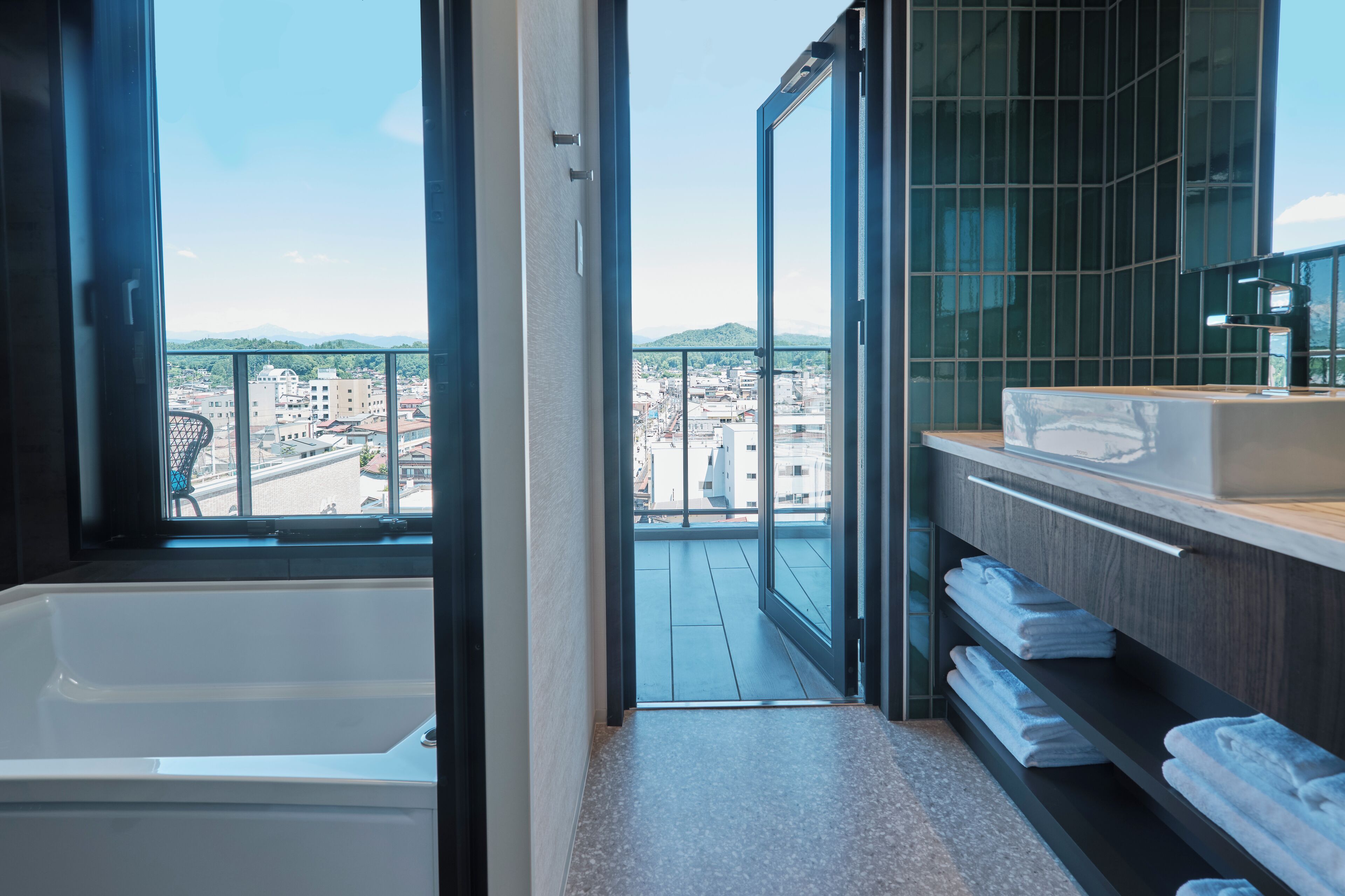 Un baño moderno con bañera, un ventanal grande y vistas a un paisaje urbano.