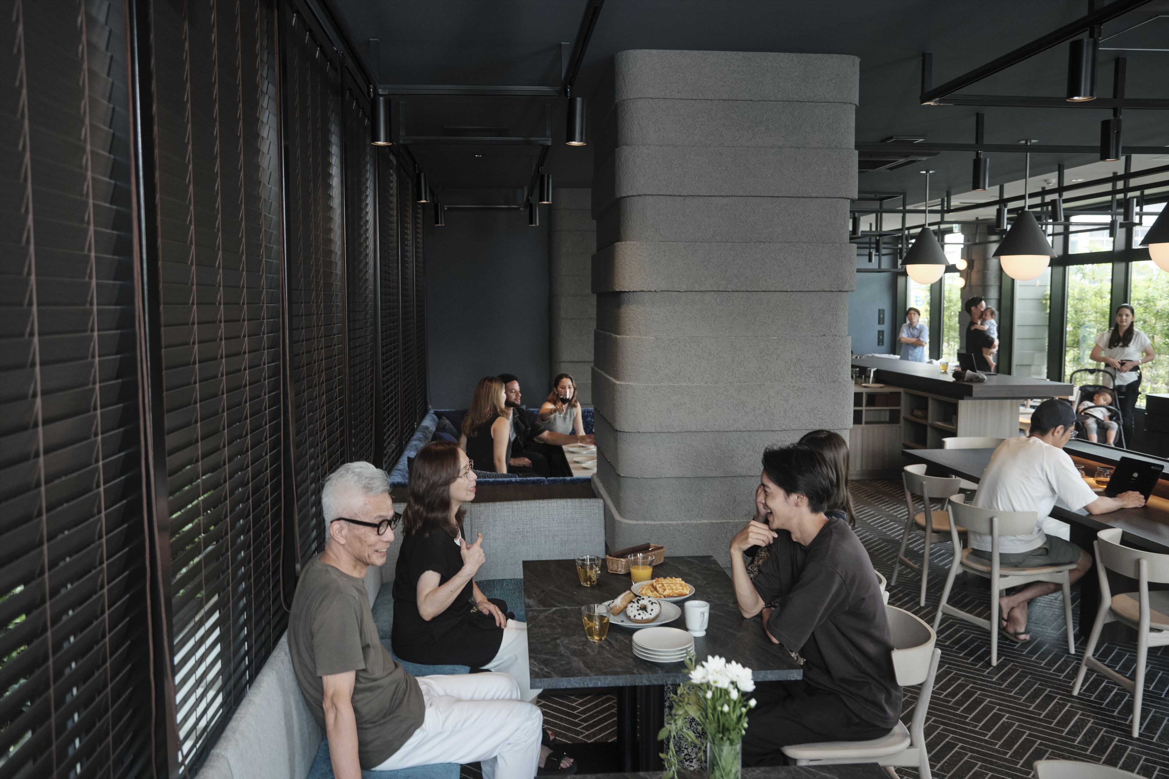 Un restaurant moderne doté d’un long comptoir, d’un espace salon et de grandes fenêtres.