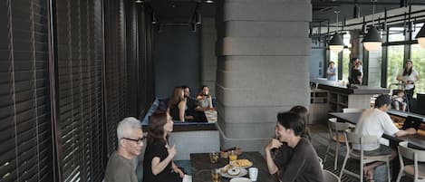 Un restaurante moderno con una barra larga, zona de mesas y amplios ventanales.