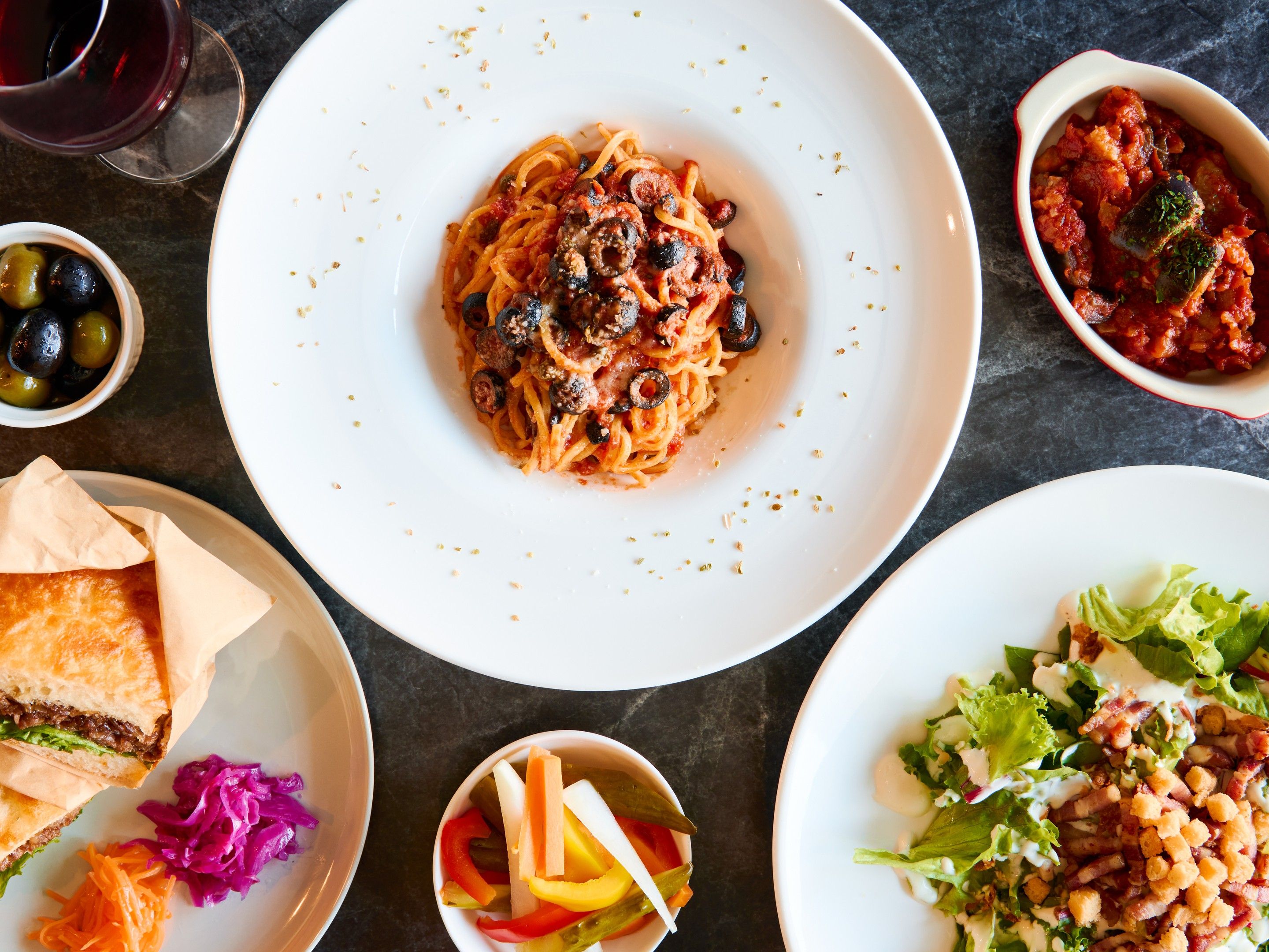 Diverse gerechten, waaronder pasta, salade en een sandwich, wat wijst op een eetsetting.