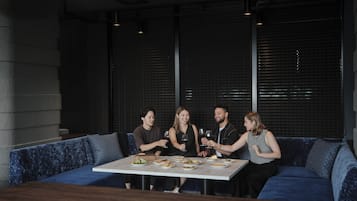Un grupo de personas sentadas en una mesa en un restaurante moderno con paredes oscuras y asientos azules.