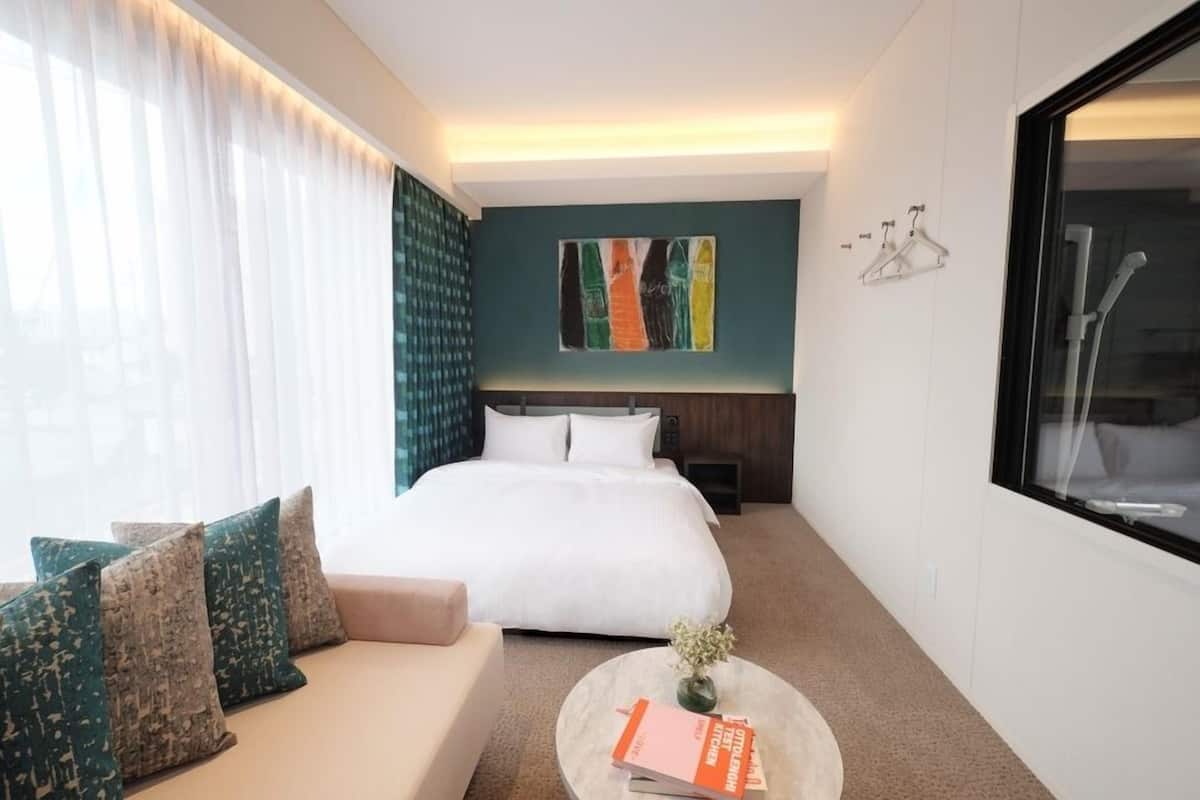 Una habitación de hotel con cama, sofá, mesa de centro y un cuadro en la pared.