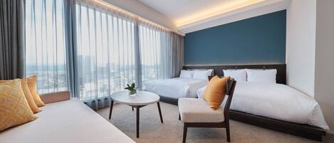 Una habitación de hotel con una cama grande, una cama más pequeña, un sofá, una silla y una mesita.