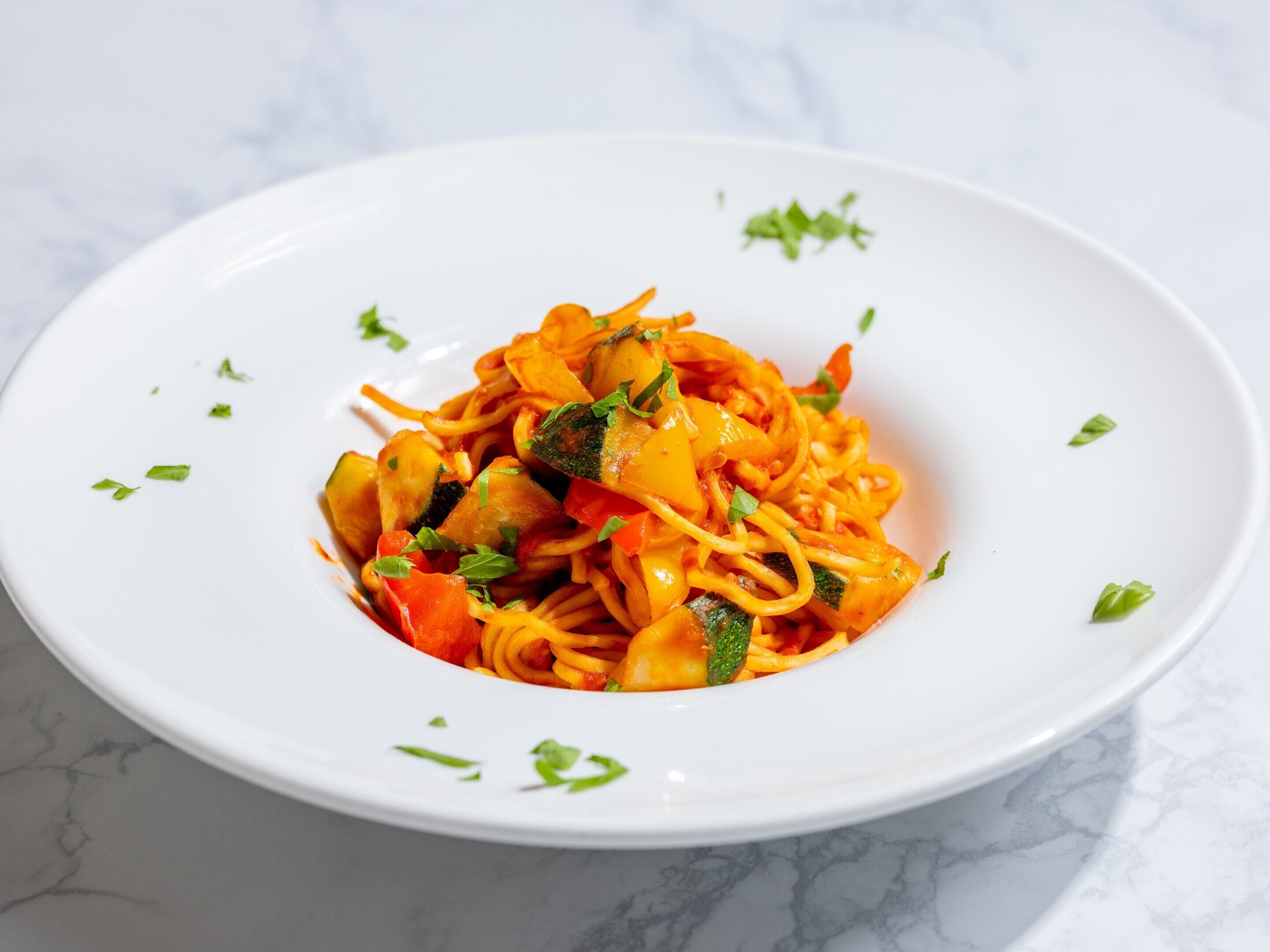 A white plate with a pasta dish garnished with herbs.