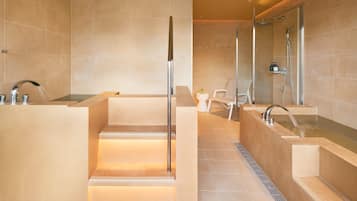 A modern bathroom with a large bathtub, a separate shower area, and a vanity with a mirror.