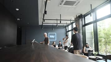 Una sala de conferencias moderna con una larga mesa, un proyector y un ventanal con vistas a zonas verdes.