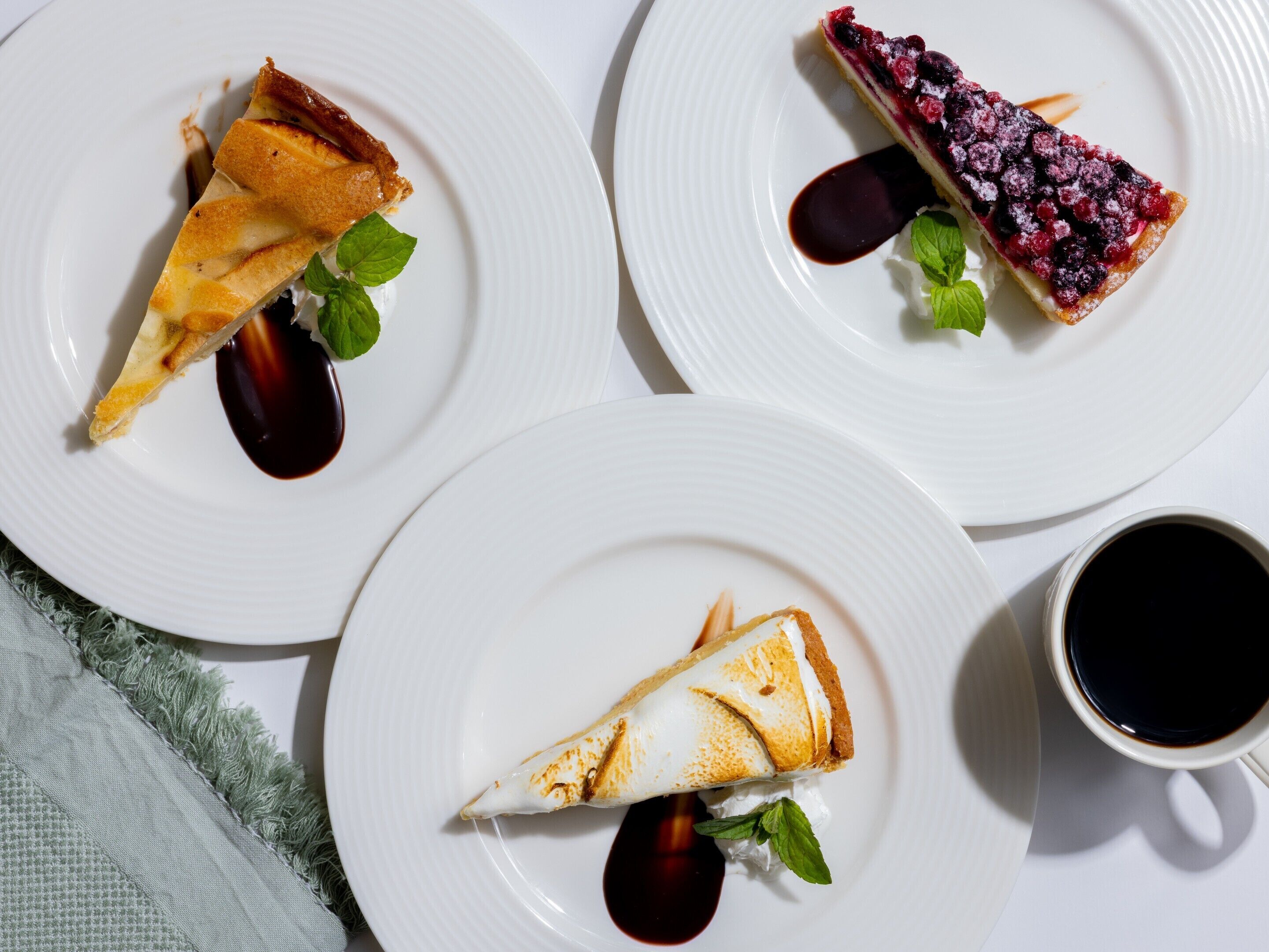 Three plates of dessert with a cup of coffee.