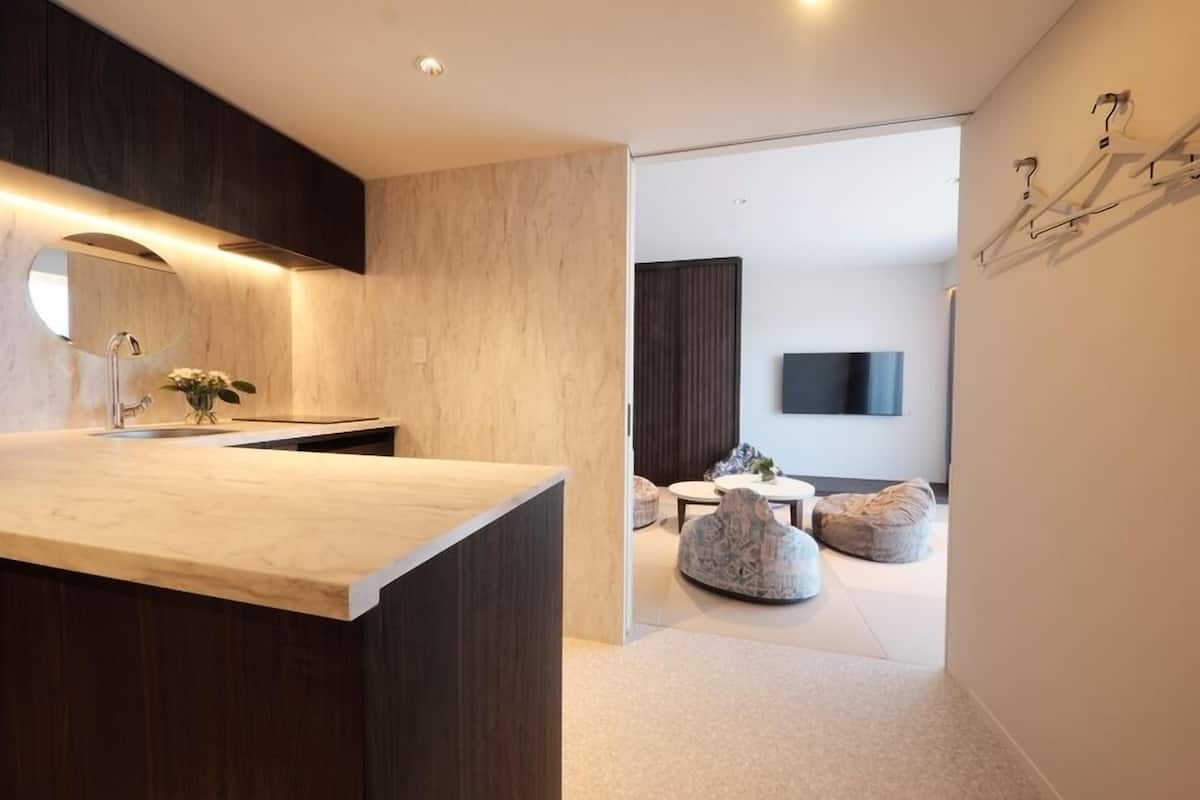 Un baño moderno con tocador de madera, espejo redondo y una planta pequeña.