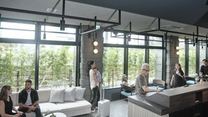 Moderni sisätila, jossa on suuret ikkunat, vastaanottotiski, oleskelualueita ja kalanruotokuvioinen lattia.