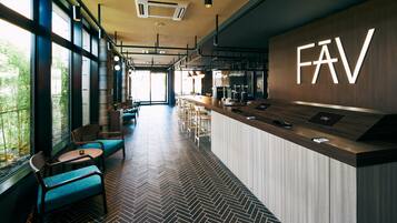 Uma área de bar moderna com piso em padrão herringbone, assentos com almofadas azuis e um letreiro 'FAV' em destaque na parede.