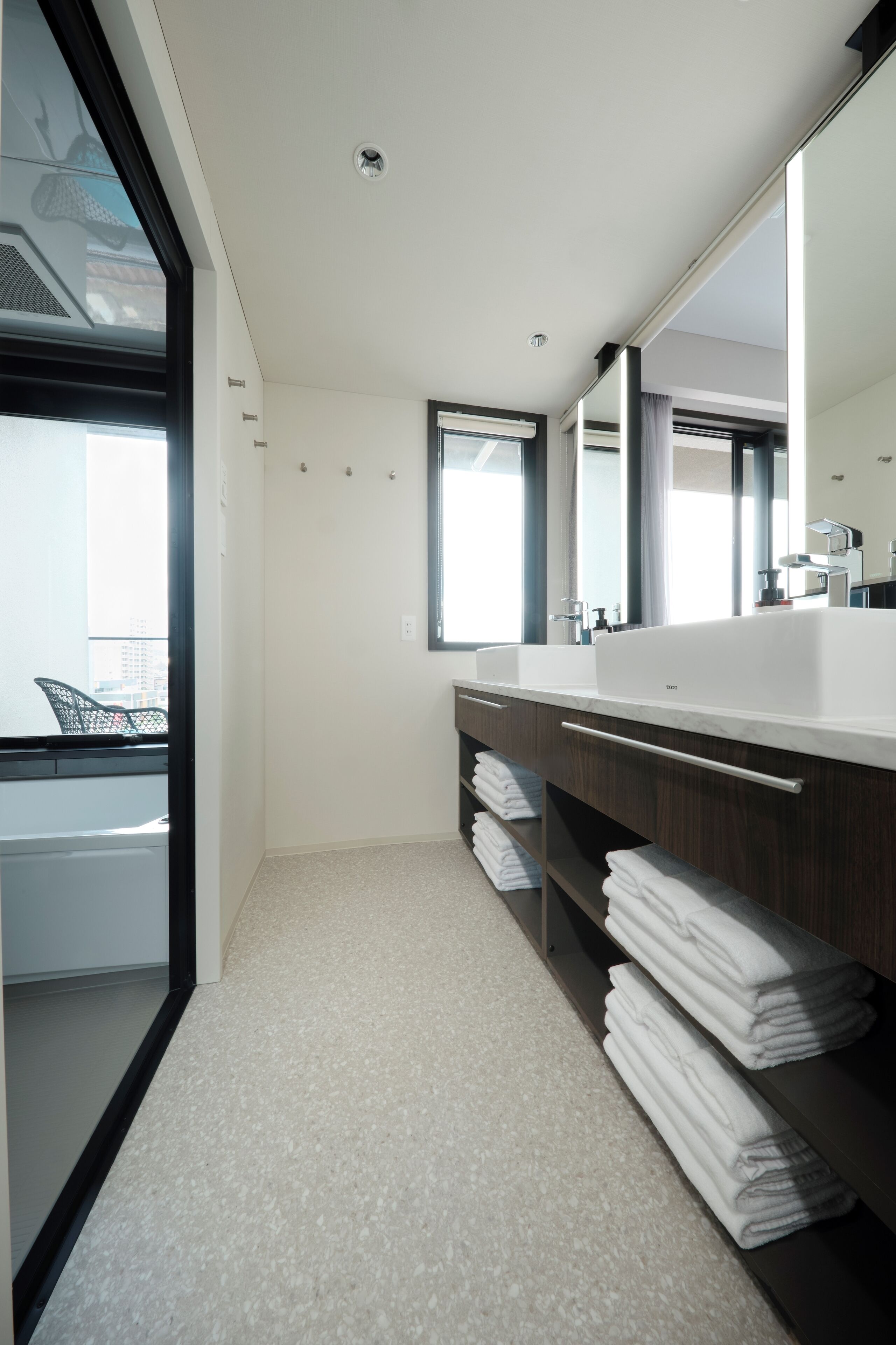 A modern bathroom with a large mirror, dual sinks, and a view of the city through a large window.