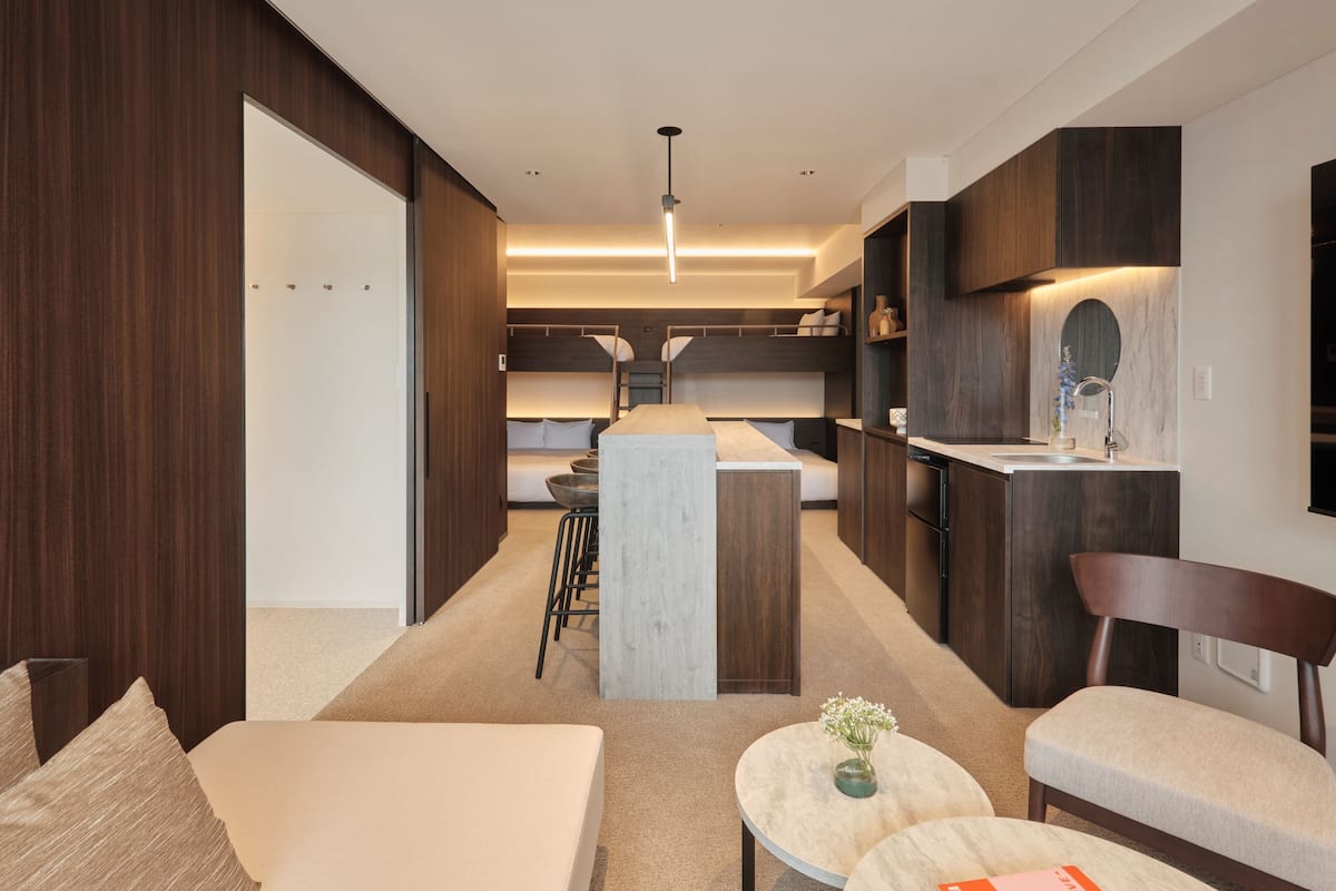 Una habitación de hotel moderna con una zona de estar acogedora, una pequeña cocina y una cama grande.
