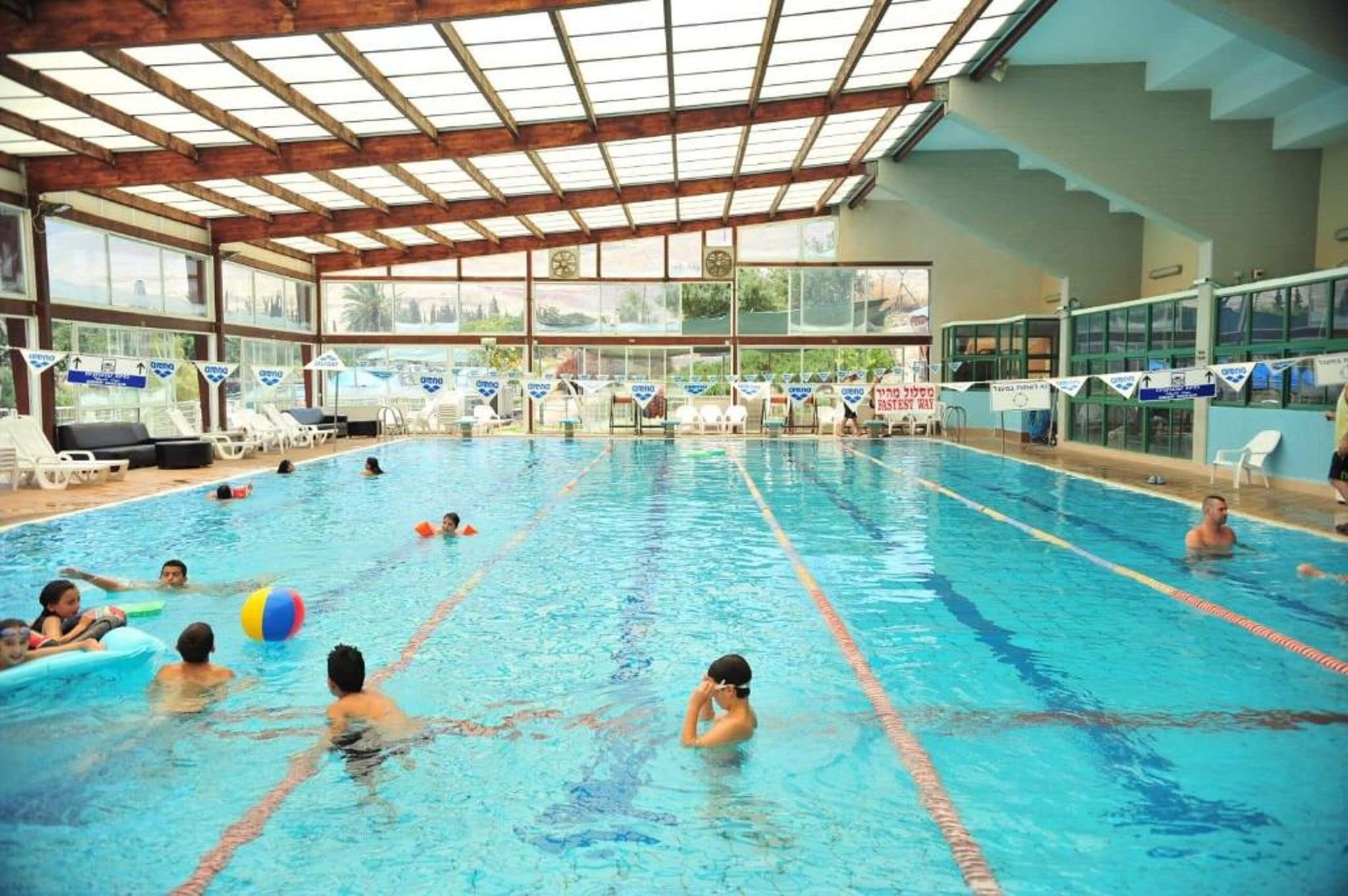 Une piscine intérieure dotée de plusieurs couloirs de nage, d’un toit ouvrant et de chaises longues.
