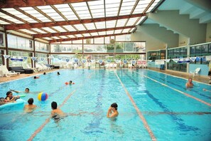 An indoor swimming pool with multiple lanes, sunroof, and lounge chairs. - Layla Glamping (Emek HaMaayanot)