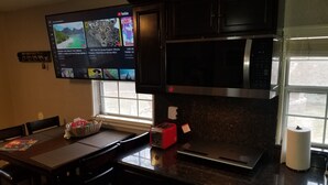 A kitchen with a TV mounted above a counter, a microwave, a toaster, and a window with a view of the outdoors. - close to downtown, to Strip Las Vegas , Arts District, (Las Vegas)