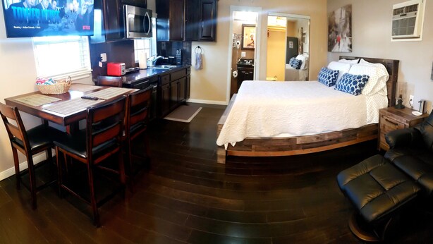 A compact room with a bed, a dining table with chairs, a kitchen area, and a TV mounted on the wall. - close to downtown, to Strip Las Vegas , Arts District, (Las Vegas)