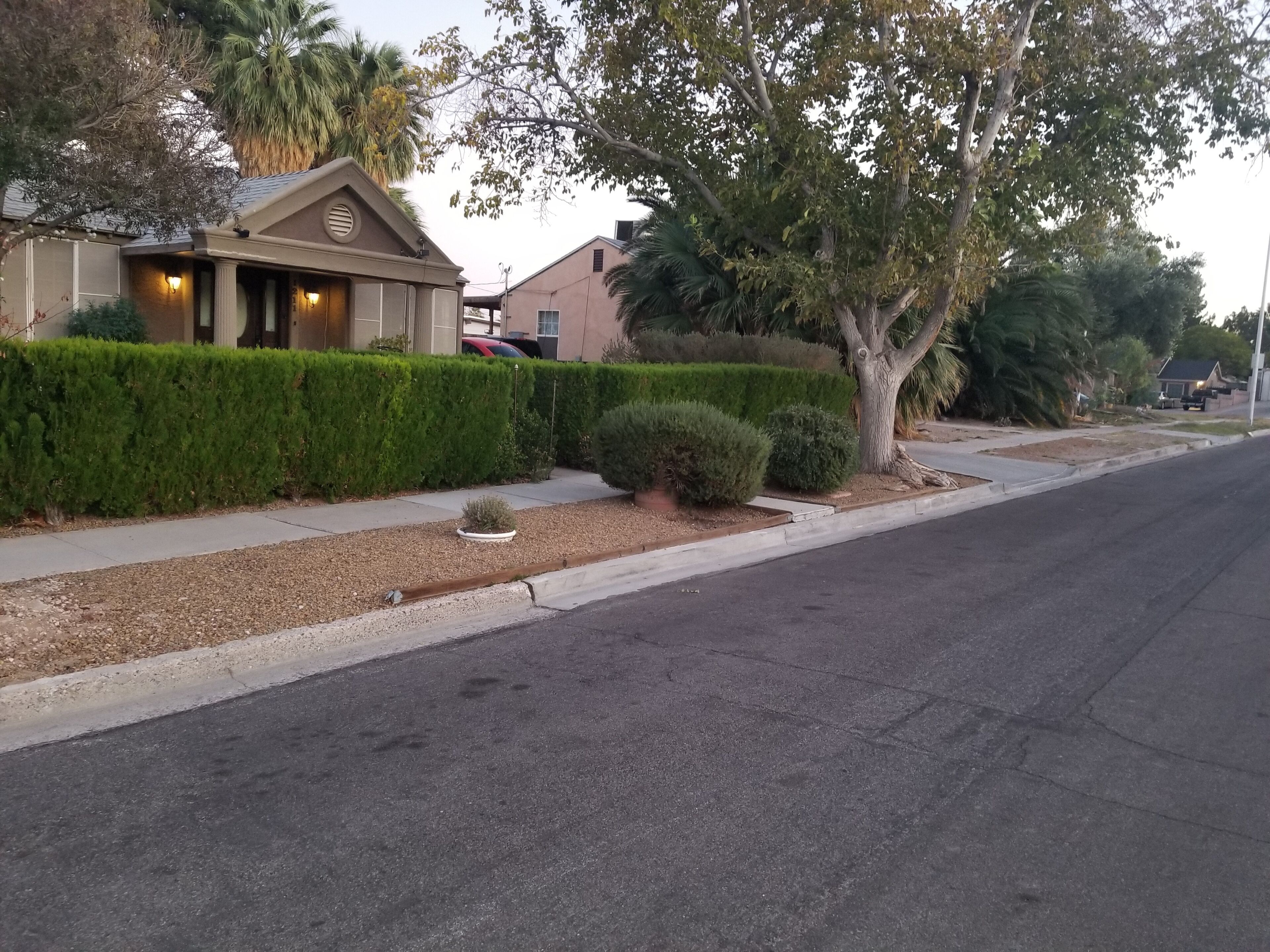 Una calle residencial con una casa que tiene un porche cubierto y una siega bien cuidada.
