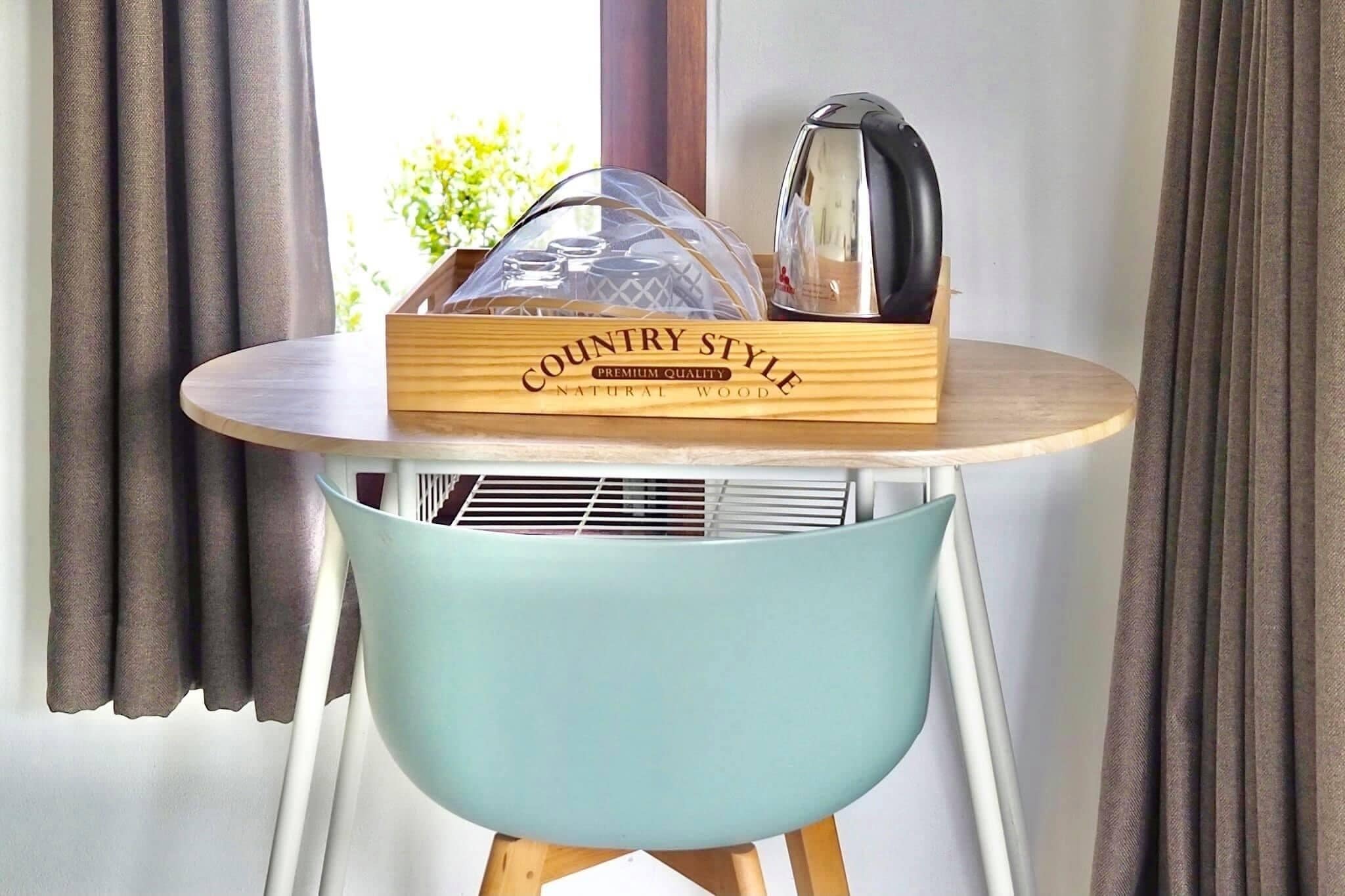 A wooden crate labeled "COUNTRY STYLE PREMIUM QUALITY NATURAL WOOD" on a round table with a light blue chair.