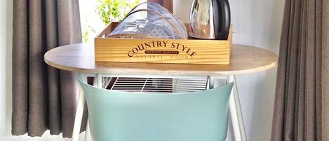 A wooden crate labeled "COUNTRY STYLE PREMIUM QUALITY NATURAL WOOD" on a round table with a light blue chair.