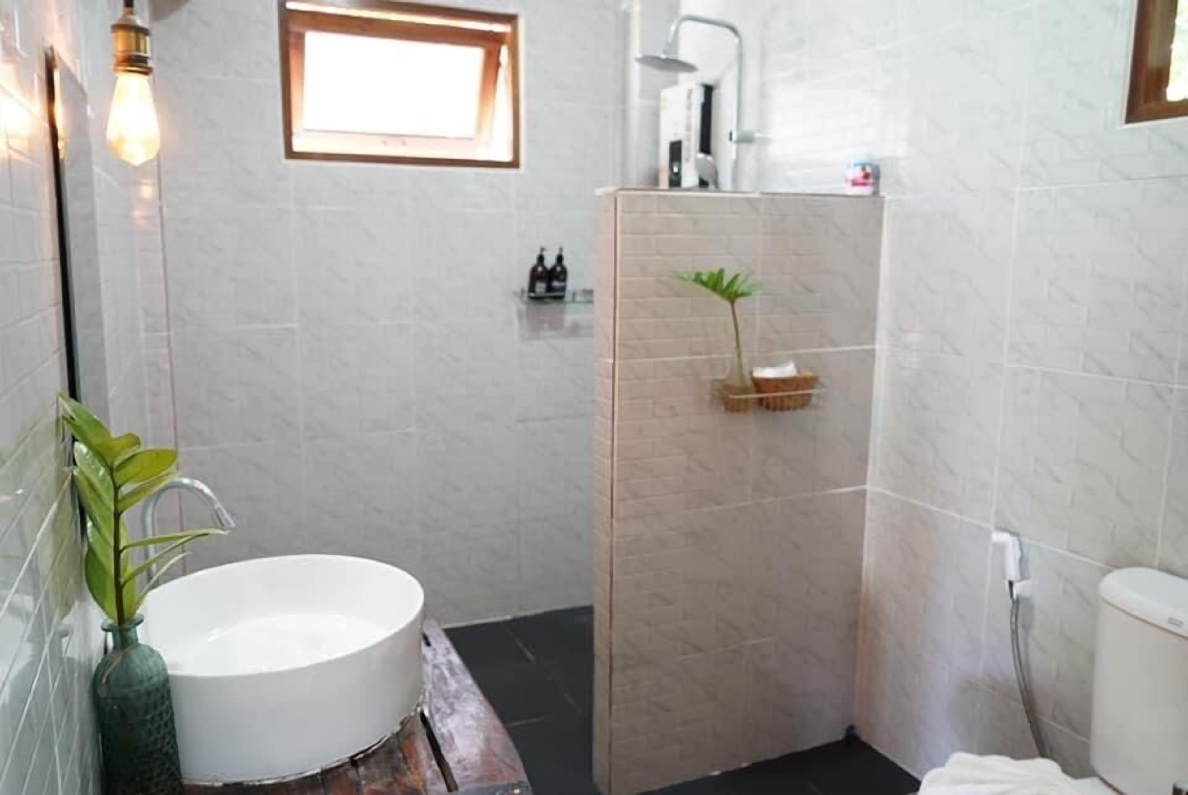 Un baño con una bañera blanca grande, una zona de ducha y un ventanal pequeño.