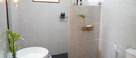 Un baño con una bañera blanca grande, una zona de ducha y un ventanal pequeño.