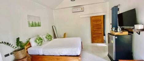 Un dormitorio con cama, un banco de madera, televisor y kitchenette.