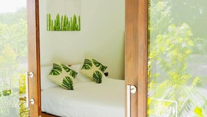A bedroom with a bed, white bedding, and tropical leaf-patterned pillows. - Maliblue resort khanom (Khanom)